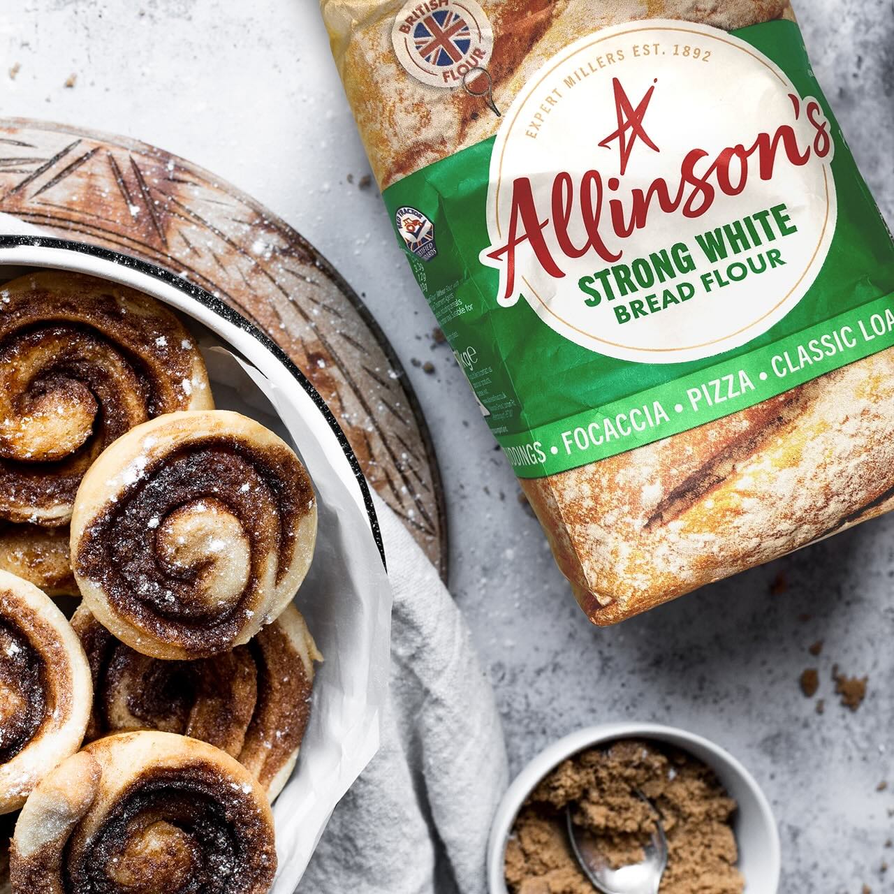 A pack of Allinson's Strong White Bread Flour alongside a plate of home made cinammon rolls.